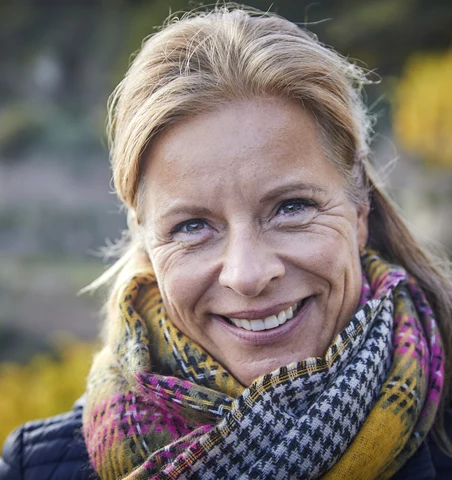 Kvinna med lyster i sin hud som står utomhus