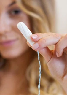 En kvinna håller upp en tampong. 