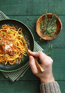Spagetti på tallrik, serverad med sås och färska kryddor.