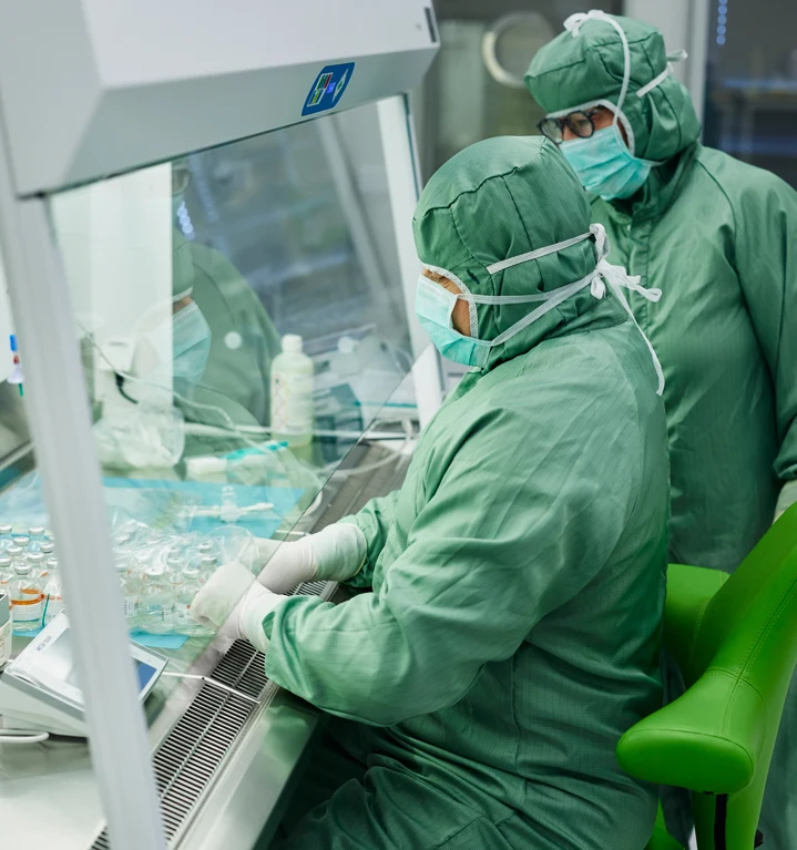 Två personer arbetar i ett laboratorium, båda har skyddskläder på sig