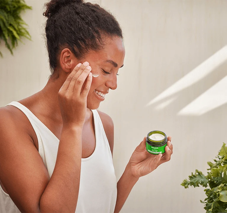 En kvinna använder en ansiktstvätt från weleda skin food.