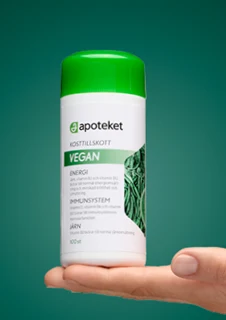 En hand visar upp kosttillskottet "VEGAN" från apoteket.