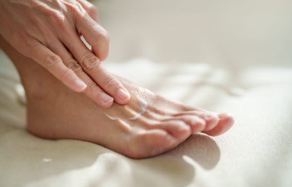 En person som smörjer in sin fot.