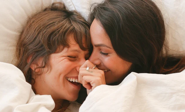 Ett par som skrattar tillsammans i en säng.