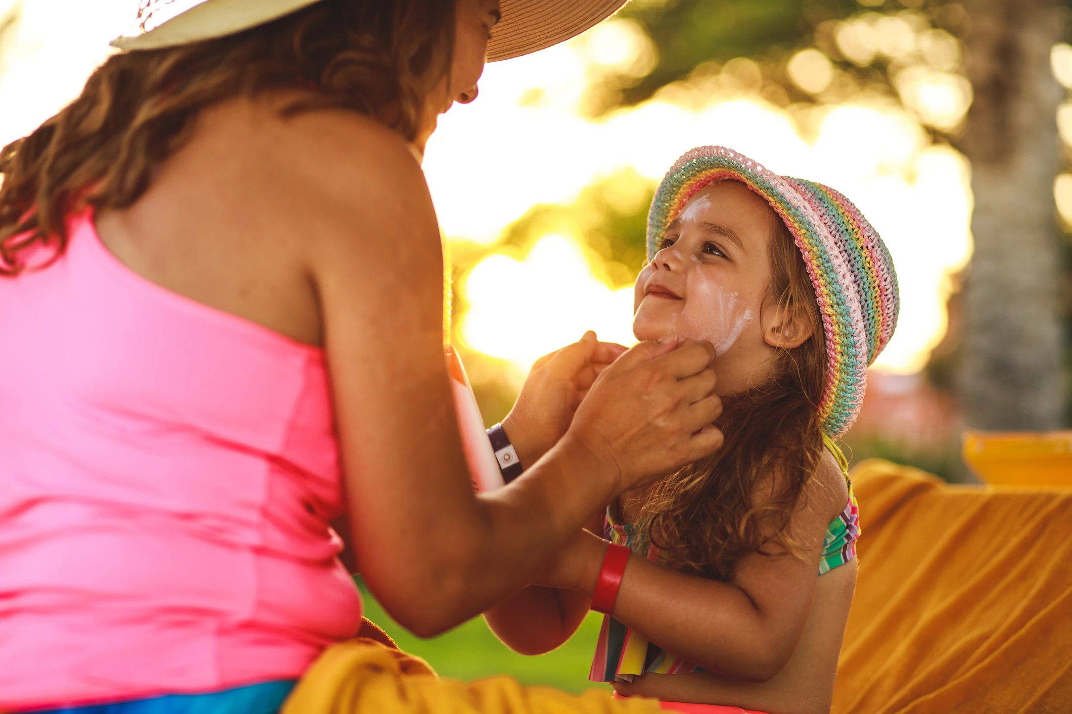 Mamma som smörjer in sin dotter med solskyddsfaktor.