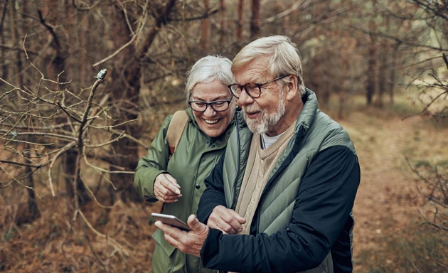 Ett äldre par som går på promenad i skogen.