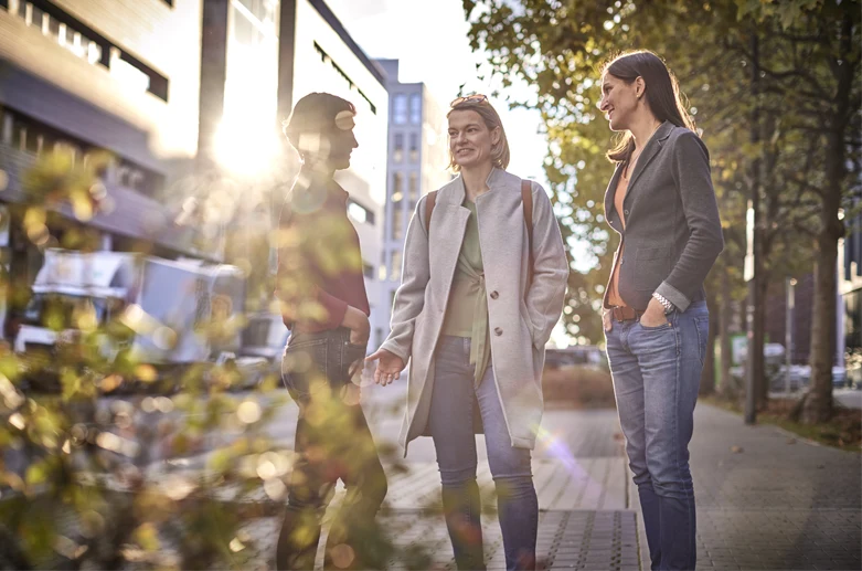 En grupp kvinnor står på en gata i solen och pratar.