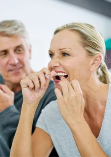 Par som rengör mellan tänderna med tandtråd i badrummet.