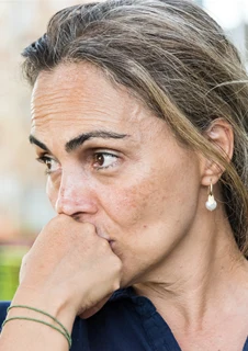 En kvinna håller ena knytnäven framför munnen och ser fundersam ut. 