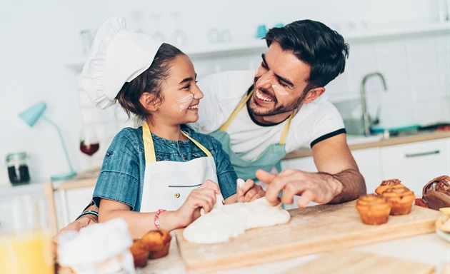 En pappa bakar tillsammans med sin dotter i ett kök. 