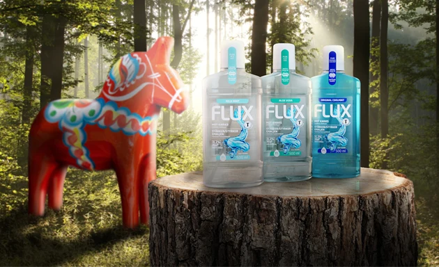En grupp Flux munsköljprodukter (Mild Mint, Aloe Vera och Original Coolmint) stående på en trästubbe i en skogsmiljö med en svensk dalahäst i bakgrunden. Produkten är förpackad i 100% återvunnen plast.